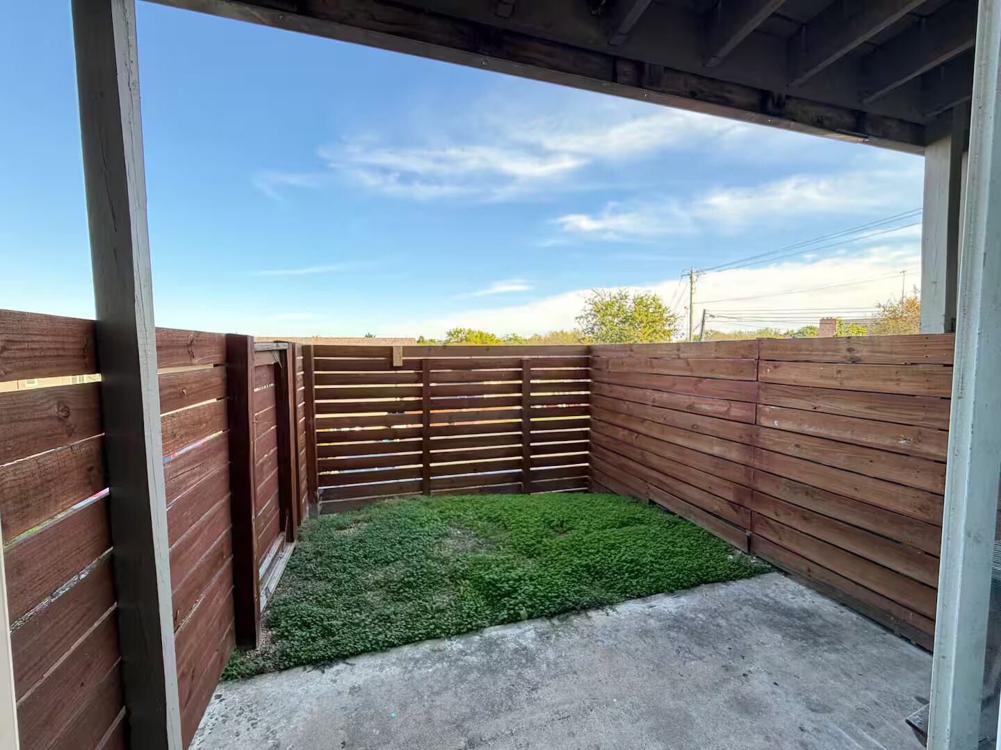 Un espace extérieur clos, doté d’une pelouse artificielle, d’un sol en béton et d’un ciel dégagé.