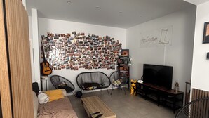 A modern living room with a wall collage, a sofa, a coffee table, and a TV. - Lemon Apartment (Schaerbeek)