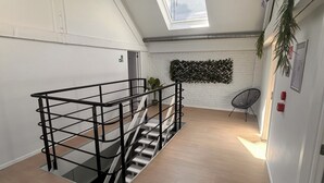 A spacious loft with a skylight, a staircase, and a white brick wall with a decorative plant. - Lemon Apartment (Schaerbeek)