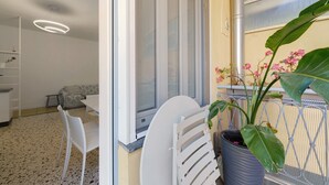 A balcony with a white chair, a potted plant, and a window with a metal grill. - Apartment 'Beautifulliguria' with Balcony, Wi-Fi and Air Conditioning (Sestri Levante)