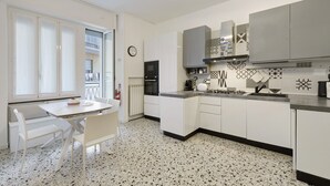 A modern kitchen with white cabinetry, a dining table with chairs, and a patterned backsplash. - Apartment 'Beautifulliguria' with Balcony, Wi-Fi and Air Conditioning (Sestri Levante)