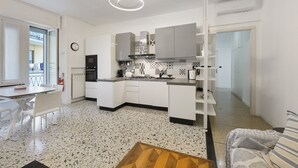 A modern kitchen with white cabinetry, a built-in oven, and a dining area with a white table and chairs. - Apartment 'Beautifulliguria' with Balcony, Wi-Fi and Air Conditioning (Sestri Levante)