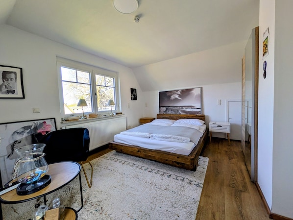 Une chambre à coucher avec un lit, un bureau, une chaise, une fenêtre et un radiateur.