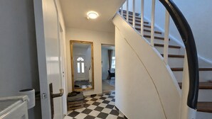 Uma escadaria com piso xadrez que leva a um quarto com espelho e porta.
