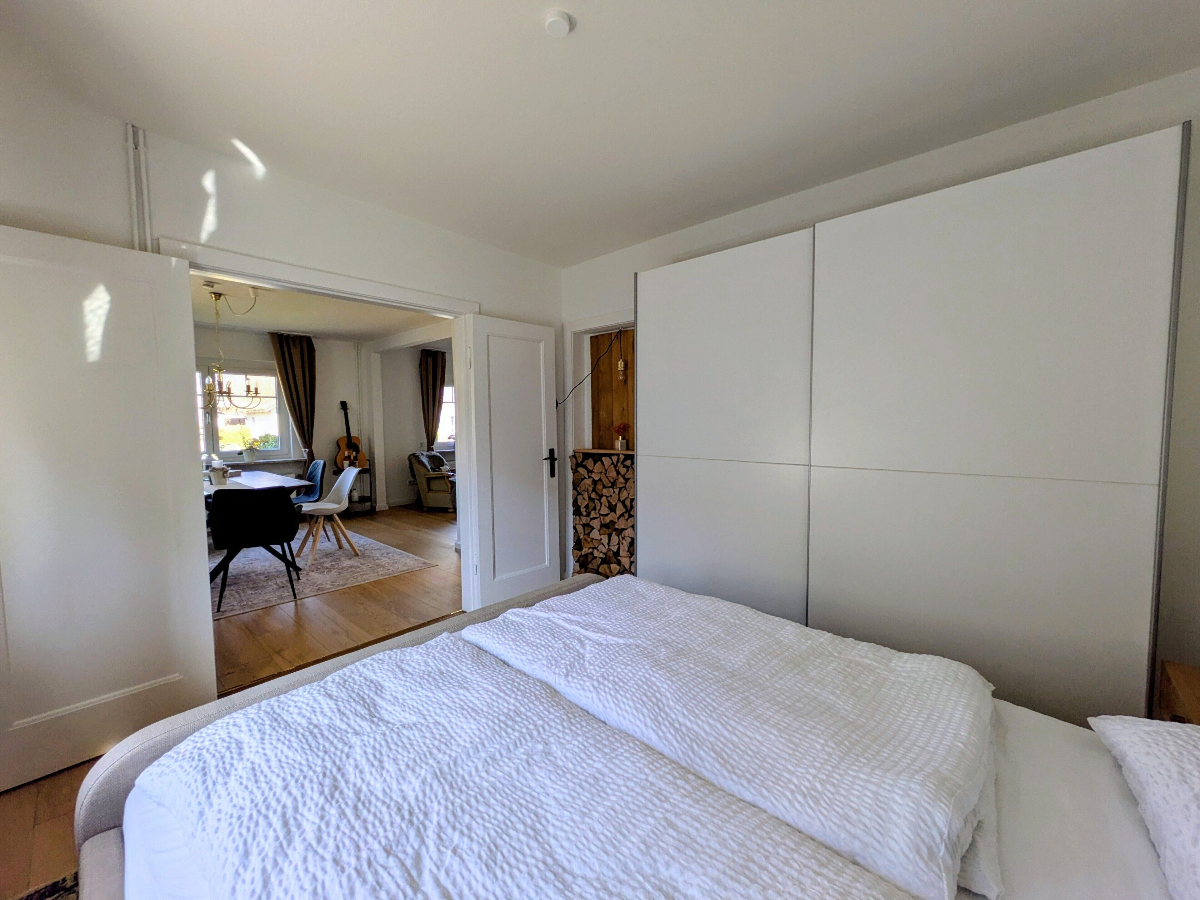 Una camera da letto con un letto, una scrivania e una chitarra sullo sfondo.