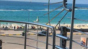 Een metalen constructie met een spiraalvormig ontwerp met uitzicht op een strand, mensen en een weg.