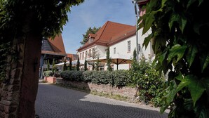 A cobblestone street lined with traditional buildings, a stone wall, and lush greenery. - Wohnkultur DSIGNIO Digital Hotel (Ladenburg)