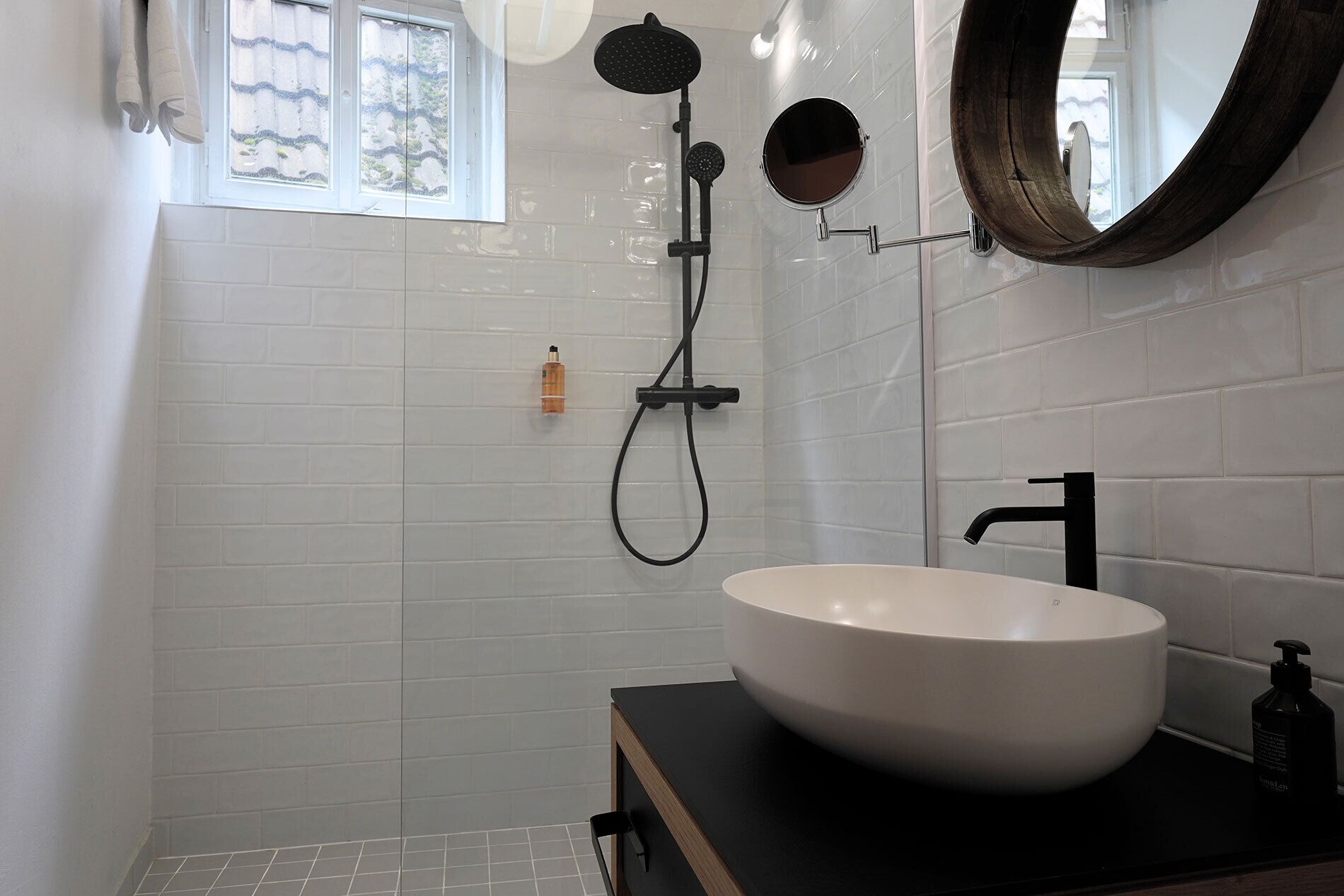 Une salle de bain avec un lavabo blanc, un robinet noir et une douchette à main.