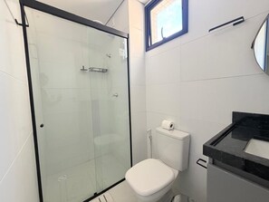 A bathroom with a glass-enclosed shower, a white toilet, and a black countertop sink. - NOA - Miramar Hospedagens (Cabedelo)