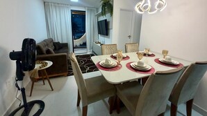 Un coin repas avec une table dressée pour quatre personnes, un canapé, un téléviseur et un ventilateur.