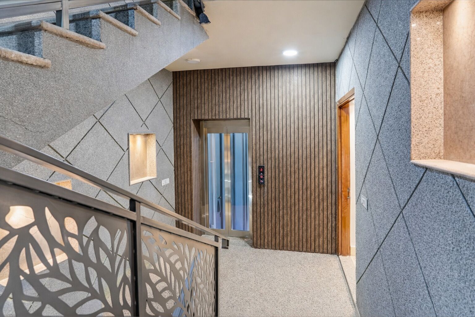 A modern interior with a staircase, a wooden panel wall, and a door with a blue stripe.