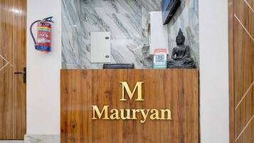 Mostrador de recepción con pared de mármol, extintor, estatua y un código QR.