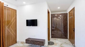 A room with a TV mounted on the wall, a wooden cabinet, and a marble floor.