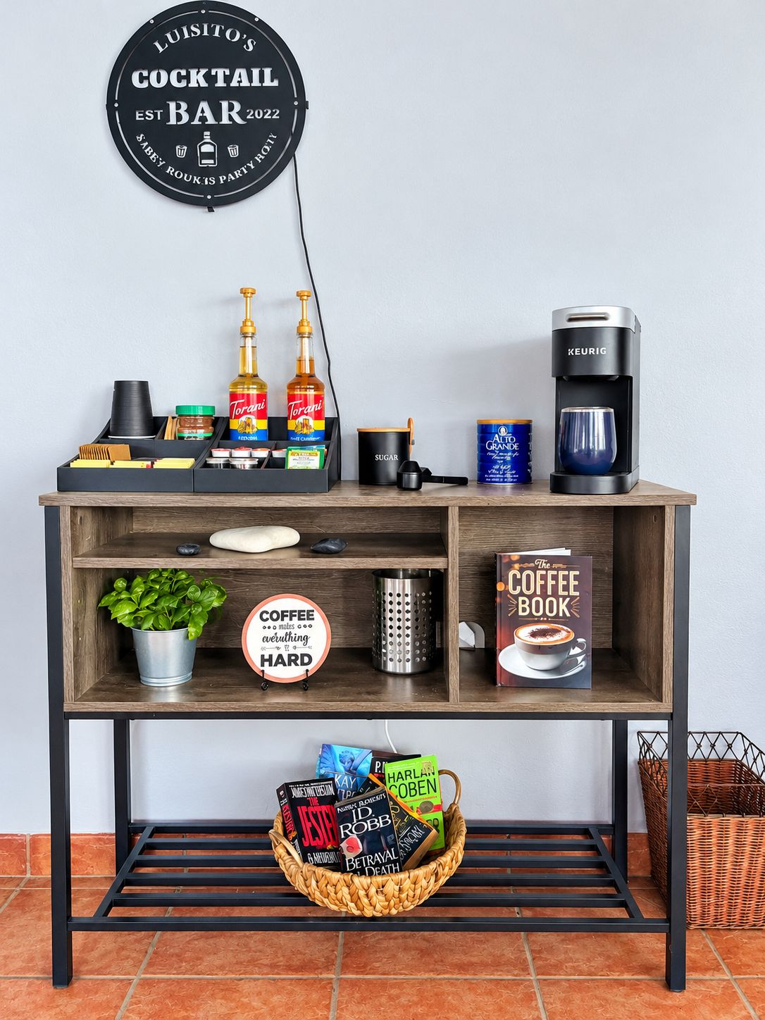 A bar setup with a coffee machine, Torani bottles, a coffee book, and a basket of books.