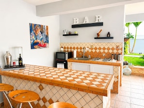 A kitchen with a bar area, a painting, and a view of the outdoors.