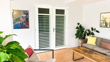 Een woonkamer met een bank, een salontafel, een potplant en een deur met ruitpanelen.
