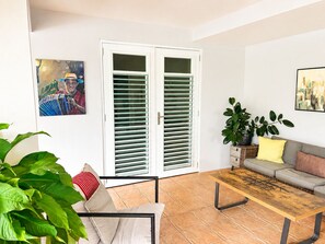 A living room with a sofa, a coffee table, a potted plant, and a door with glass panels.