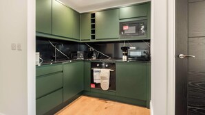 A compact kitchen with green cabinets, a microwave, and a built-in oven. - Contemporary Spacious Studio in Central Sheffield (Sheffield)