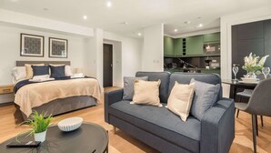 A modern hotel room with a bed, sofa, dining table, and kitchenette. - Contemporary Spacious Studio in Central Sheffield (Sheffield)