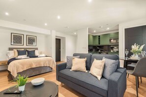 Ein modernes Hotelzimmer mit Bett, Schlafsofa, Esstisch und Küchenzeile.