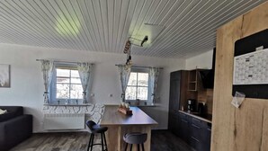 A kitchen with a wooden countertop, two bar stools, a dining table, and a refrigerator.