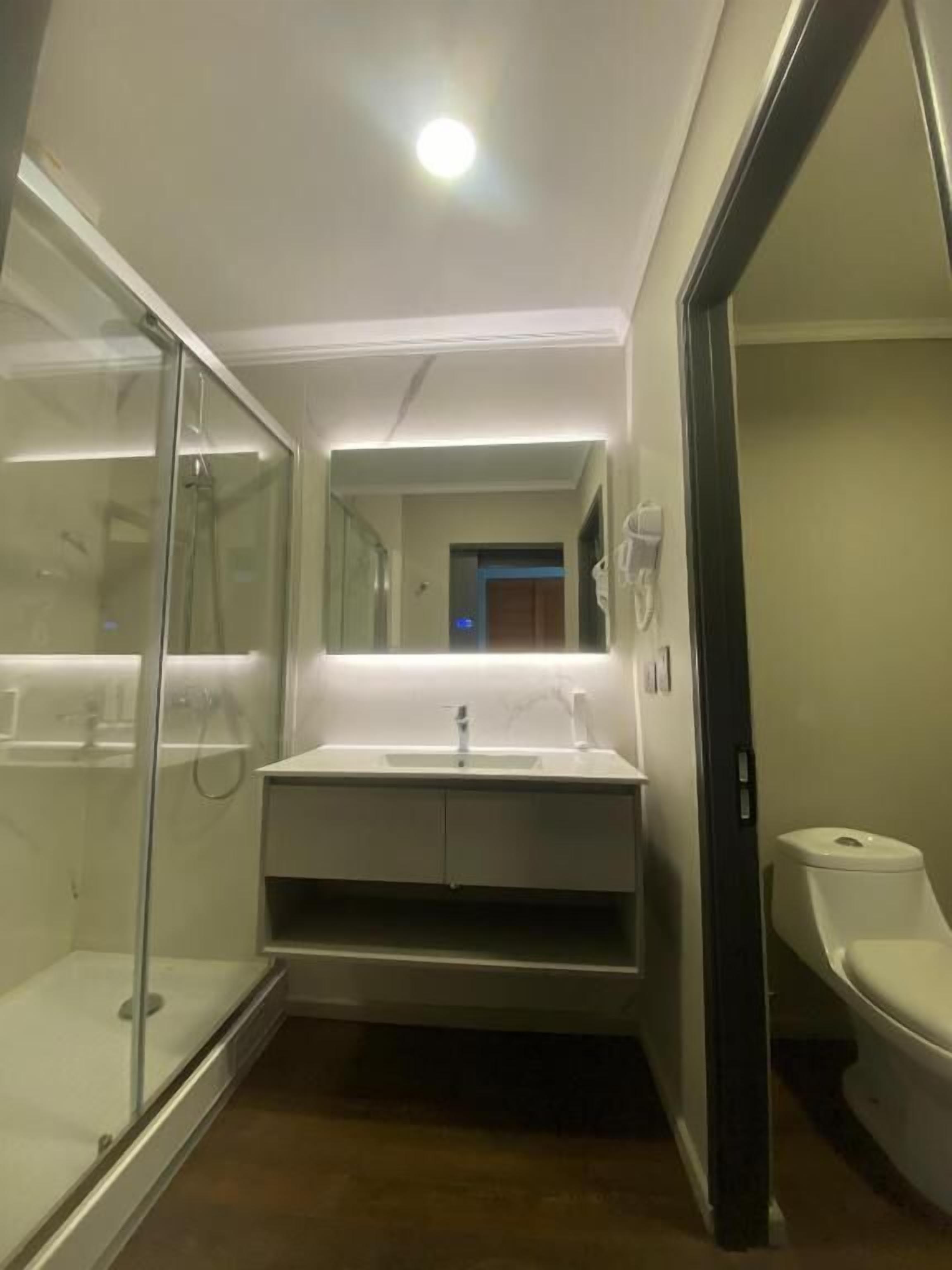Un baño moderno con cabina de ducha de vidrio, lavamanos blanco y un inodoro.