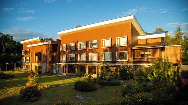 Un edificio de varios pisos con techo plano, ventanas amplias y un jardín bien cuidado.