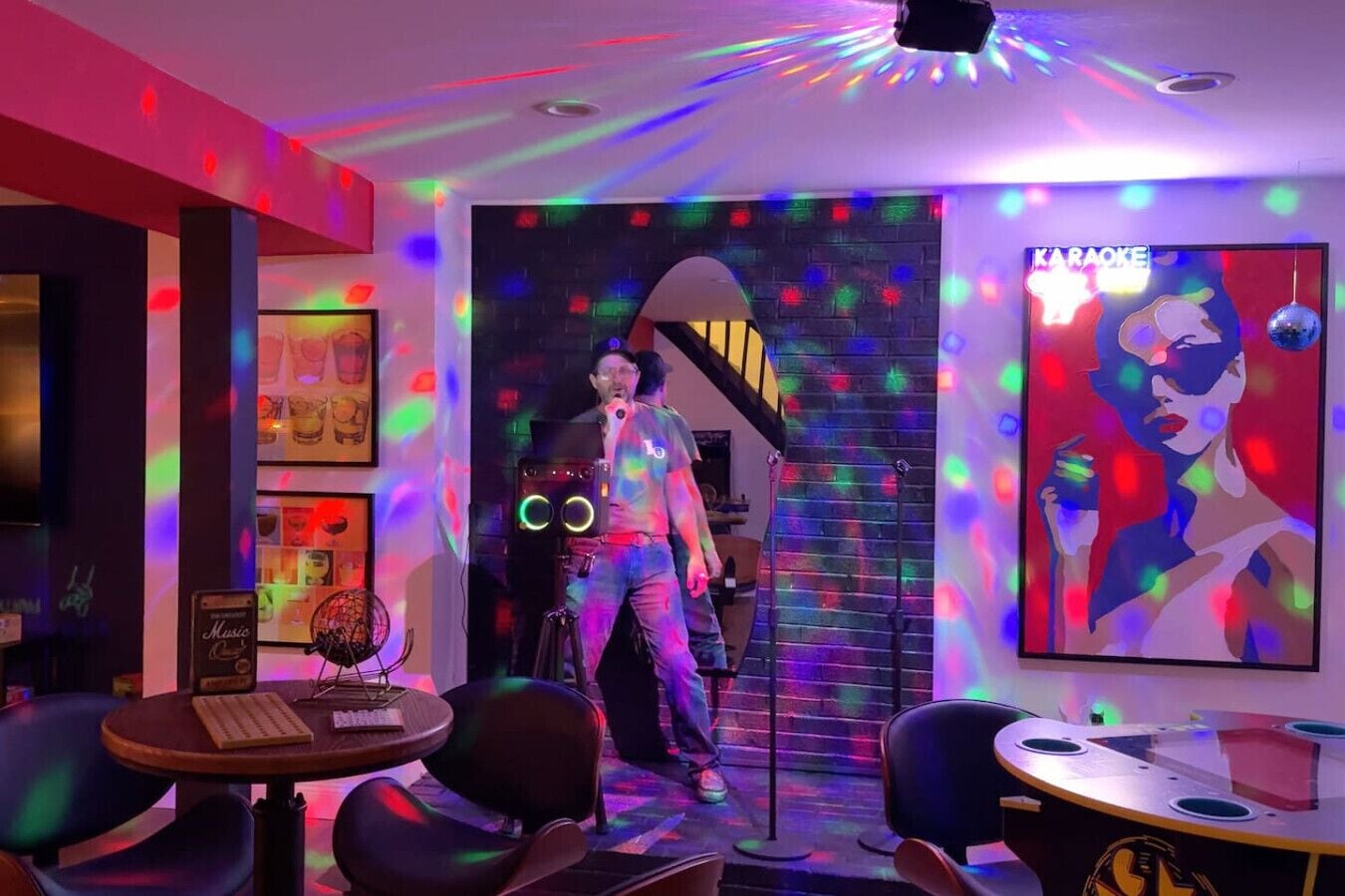 Una habitación con una escalera, equipo de karaoke y un cartel en la pared.