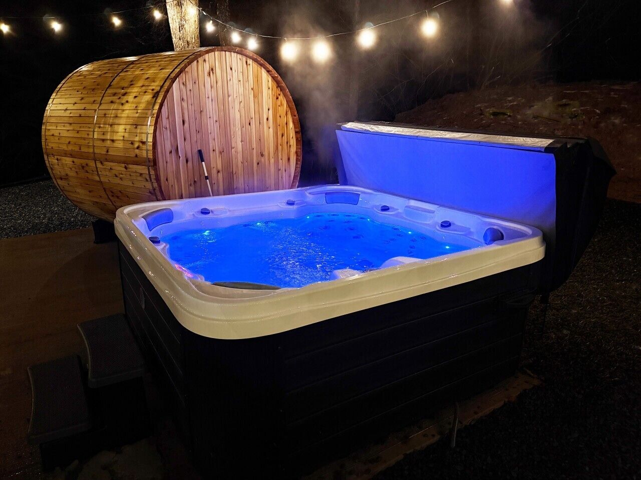 A hot tub with a wooden barrel and string lights in the background.