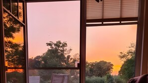 Une pièce avec vue sur le coucher de soleil, une table à manger avec des verres et des assiettes, et un canapé.