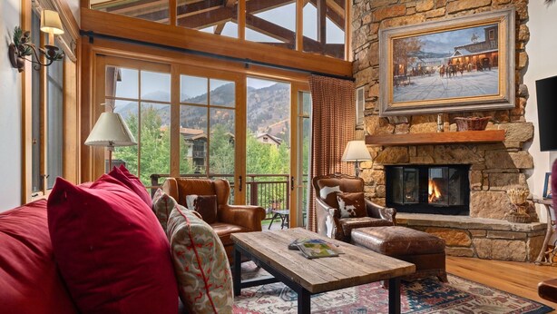 Una sala de estar acogedora con chimenea, ventanas amplias y una pared de piedra.