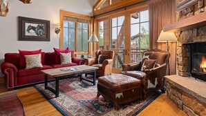 Una sala de estar acogedora con chimenea, muebles de cuero y un amplio ventanal con vistas panorámicas.