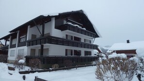 A multi-story building with a sloped roof, surrounded by snow.