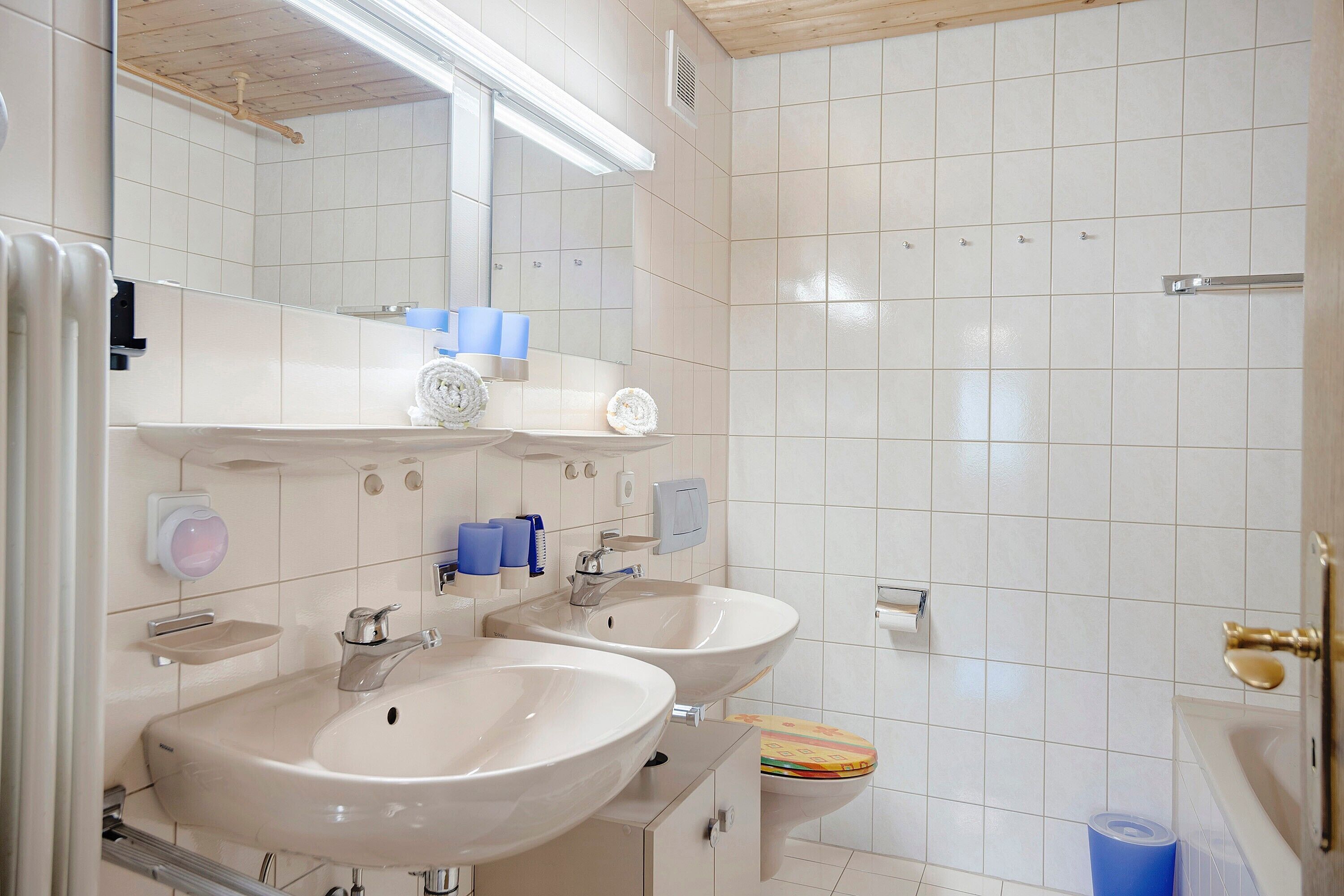 Un baño con dos lavamanos, un espejo, un inodoro y una zona de ducha.