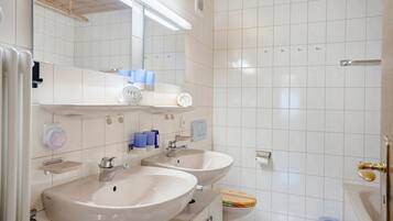 Un baño con dos lavamanos, un espejo, un inodoro y una zona de ducha.
