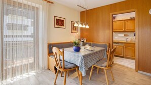 A dining area with a table set for four, wooden chairs, a vase with flowers, and a kitchen visible through an open door. - Apartment "Vogel" with Mountain View, Shared Garden, and Wi-Fi (Wertach)