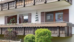 A two-story building with wooden balconies, a hanging lantern, and a wooden fence. - Apartment "Vogel" with Mountain View, Shared Garden, and Wi-Fi (Wertach)