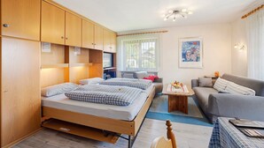 A room with a bunk bed, a sofa, a small table, and a window with curtains. - Apartment "Vogel" with Mountain View, Shared Garden, and Wi-Fi (Wertach)
