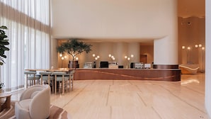 Eine moderne Lobby mit Empfangsschalter, Sitzgelegenheiten und einer großen Pflanze.