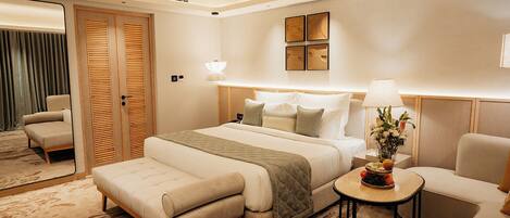 Een hotelkamer met een bed, een bank, een kleine tafel met fruit, een lamp en een plafondventilator.