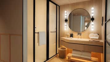 Un baño moderno con tocador de madera, un espejo redondo con iluminación, un banco y un cesto de basura.