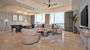 Ein geräumiges Wohnzimmer mit großem Sofa, Essbereich, Flachbildfernseher und Blick auf die Stadt.