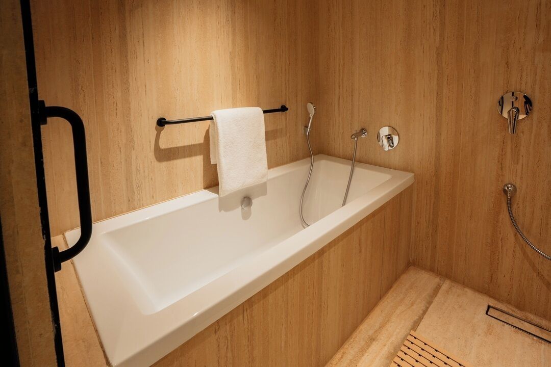 A modern bathroom with a white bathtub, wooden panel walls, and a towel rack.