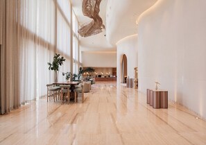 A spacious lobby with a marble floor, a reception desk, seating area, and a decorative ceiling feature. - The Forum Hotel and Convention (Sanand)