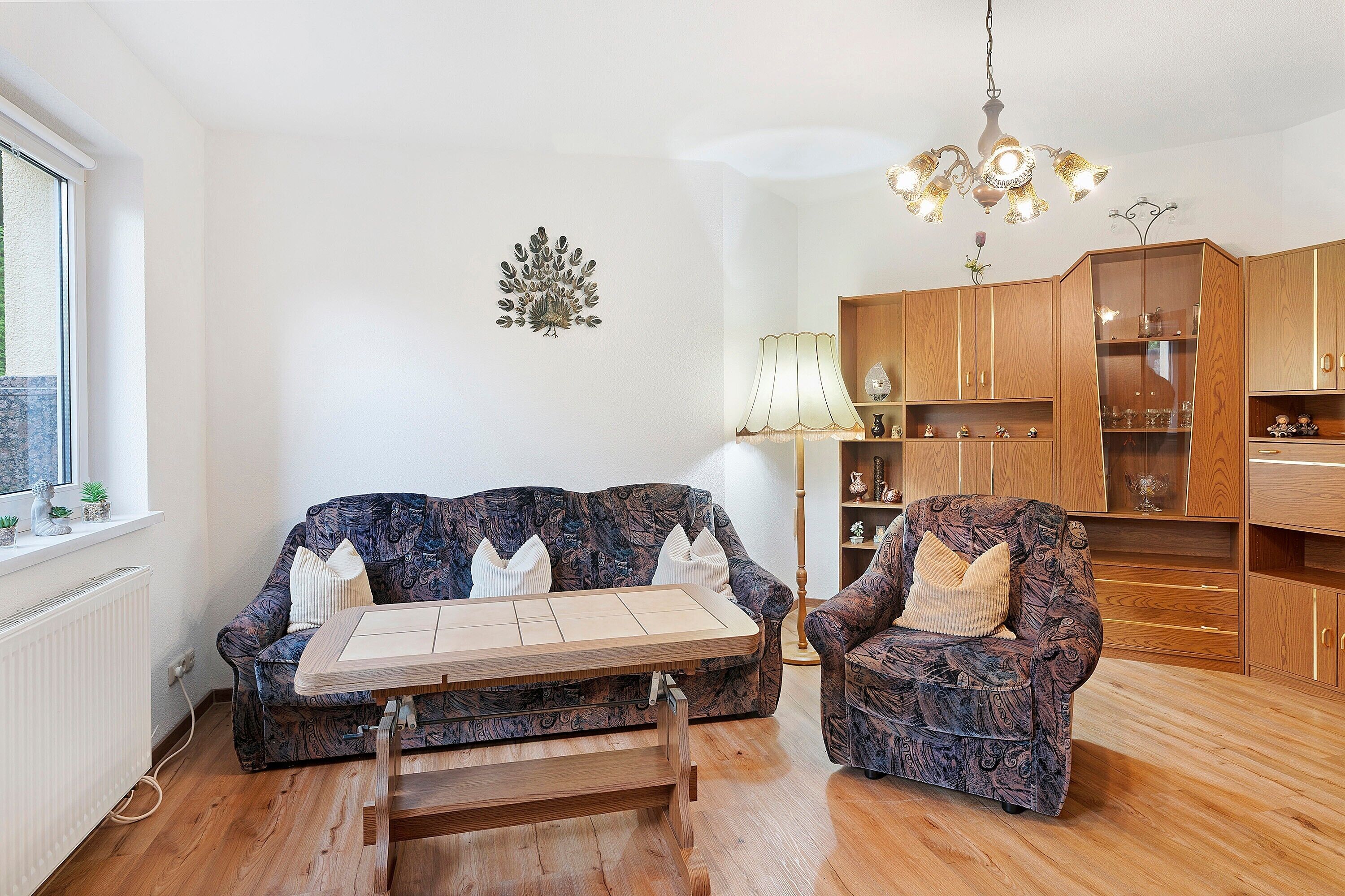 Un salon comprenant un canapé, un fauteuil, une table basse en bois et un lustre.