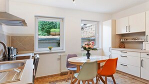 A modern kitchen with a dining table, chairs, and a view of the garden. - Holiday Home 'Ferienwohnung Sehr Ruhig' with Private Garden and Wi-Fi (Pößneck)