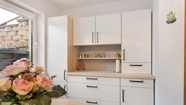 A modern kitchen with white cabinets, a wooden countertop, and a vase with flowers on the table. - Holiday Home 'Ferienwohnung Sehr Ruhig' with Private Garden and Wi-Fi (Pößneck)