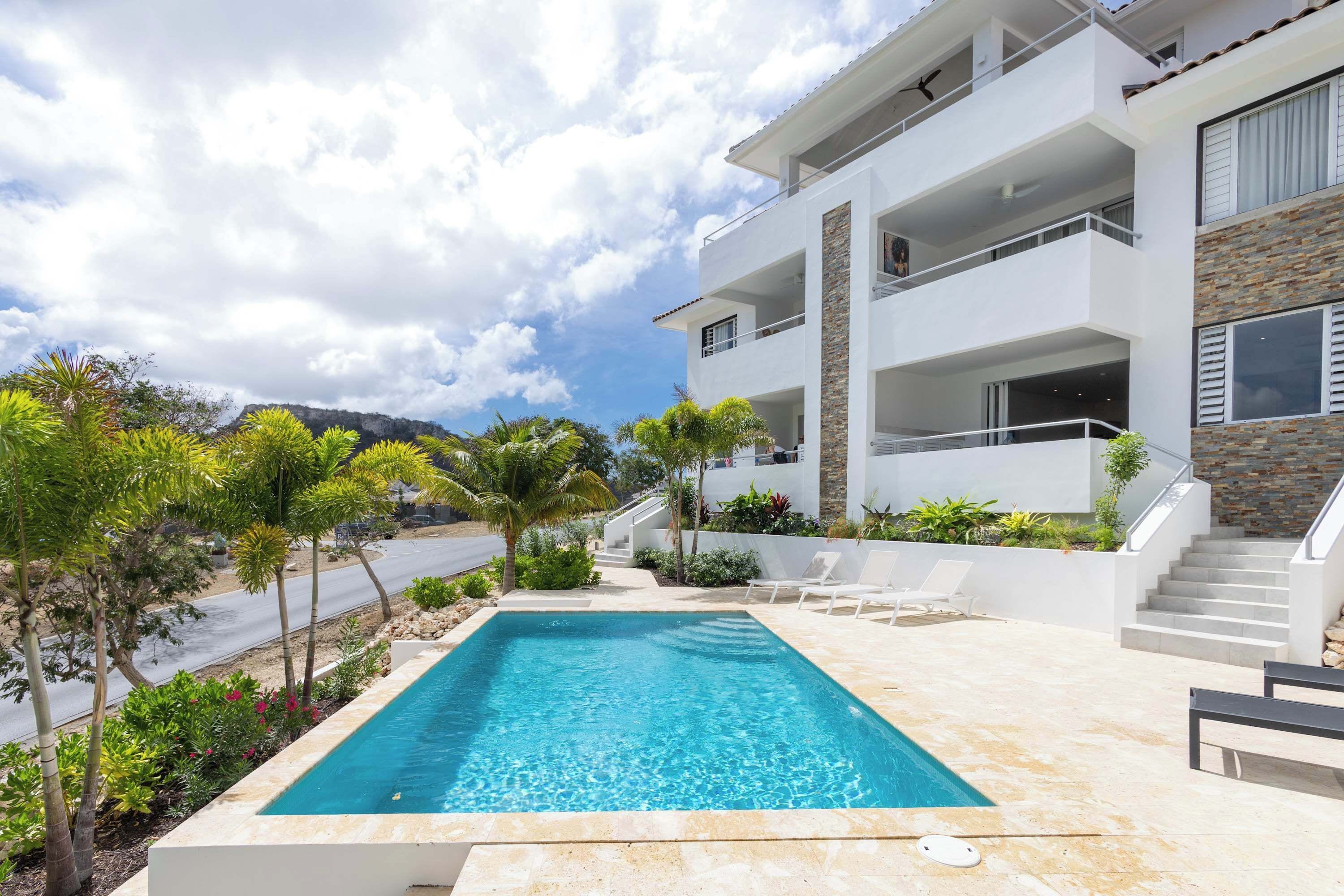 A modern building with a swimming pool, outdoor seating, and a staircase leading to the upper floors.