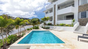 Um edifício moderno com piscina, área de estar ao ar livre e escadaria que dá acesso aos andares superiores.