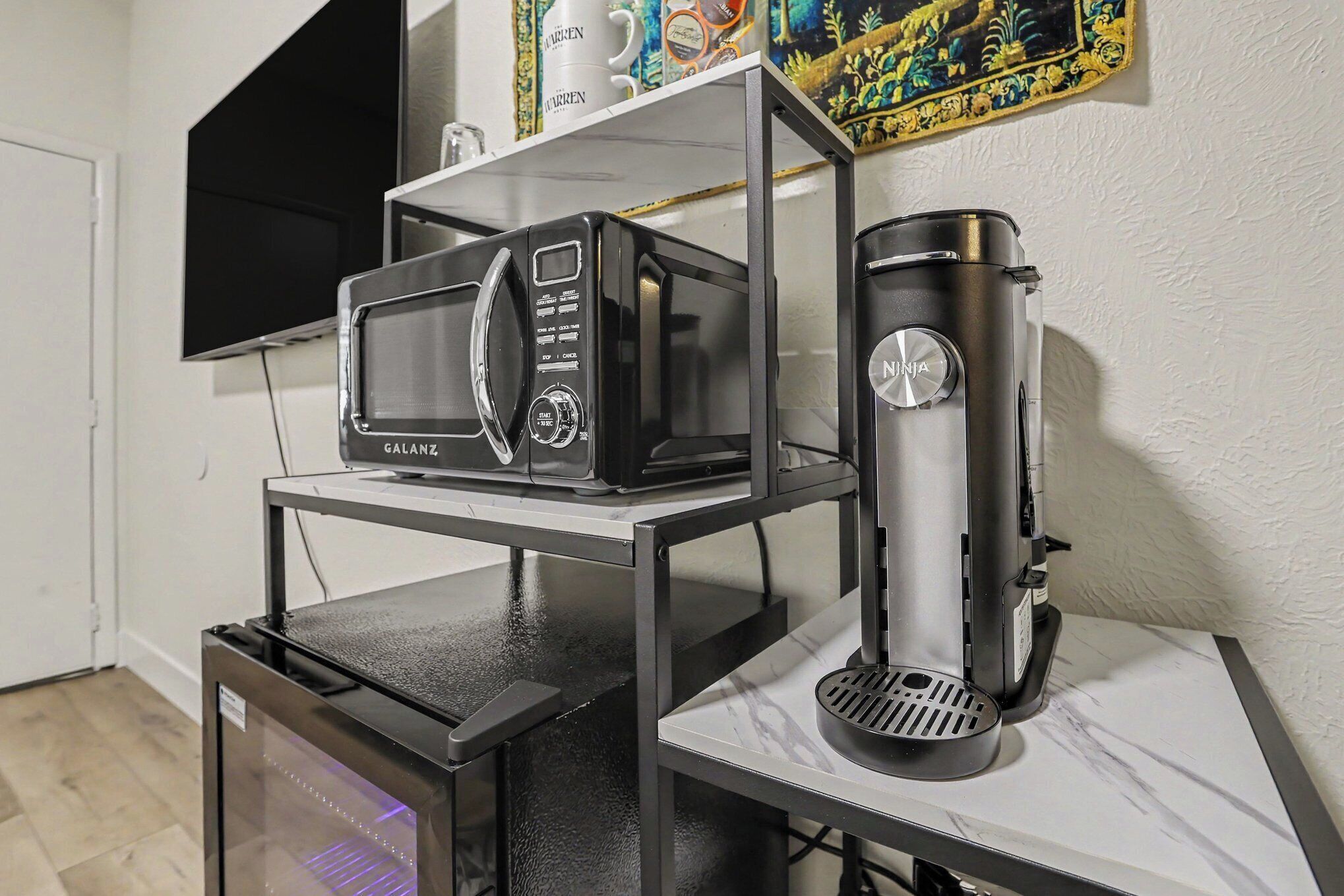 A kitchen with a microwave, coffee maker, and a small refrigerator.